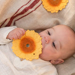 A baby holding and chewing the Oli & Carol Sun The Sunflower Baby Teether