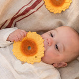 A baby holding and chewing the Oli & Carol Sun The Sunflower Baby Teether