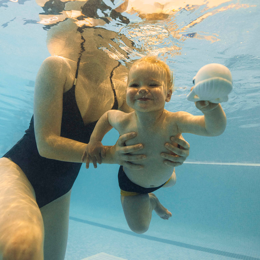 Child swimming and playing with the Oli and Carol Walter the Whale bath toy.