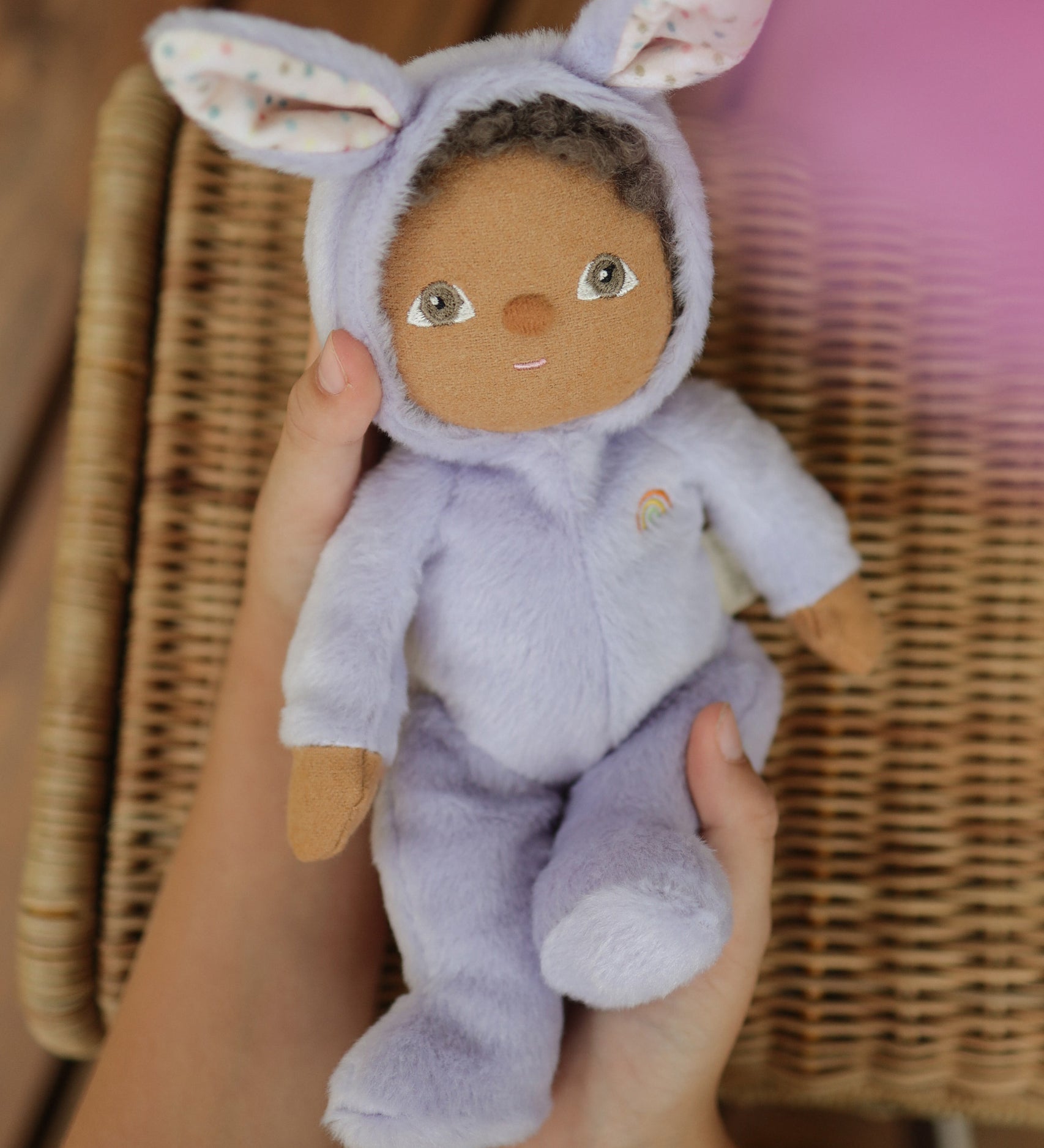 A close up of an Olli Ella purple coloured Babs Bunny Dinky Dinkum Doll in a child's hands.