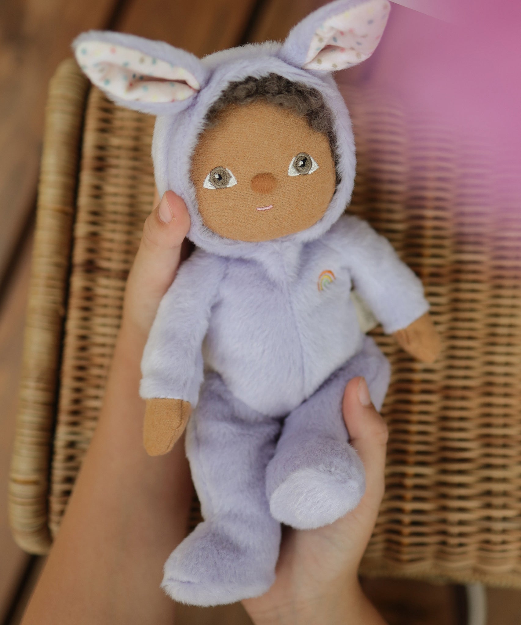 A close up of an Olli Ella purple coloured Babs Bunny Dinky Dinkum Doll in a child's hands.