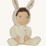 Olli Ella cream coloured Basil Bunny Dinky Dinkum Doll in a seated position with the bunny ear hood up showing the dinky dolls brown coloured curly hair peeping out at the  front