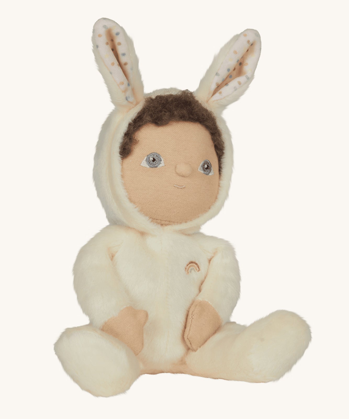 Olli Ella cream coloured Basil Bunny Dinky Dinkum Doll in a seated position with the bunny ear hood up showing the dinky dolls brown coloured curly hair peeping out at the  front