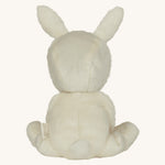 Olli Ella cream coloured Basil Bunny Dinky Dinkum Doll in a seated position facing away from the camera showing the back of the teddy.