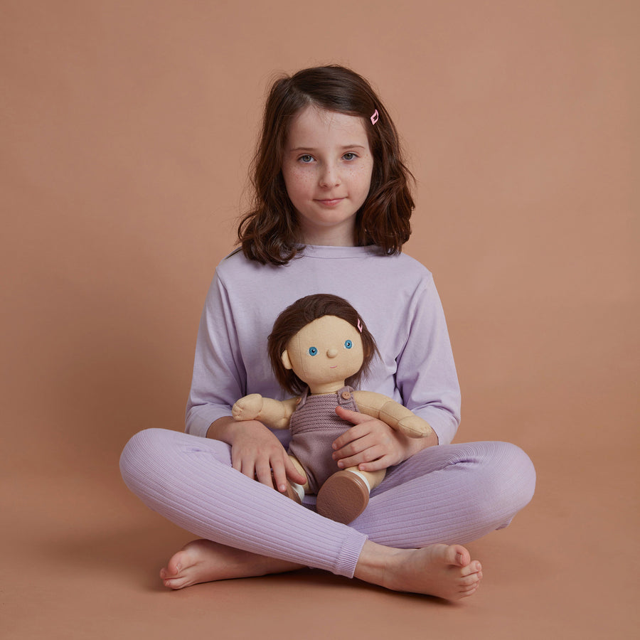 soft bodied Dinkum Doll with hair tied up in little bunches at the side of their head sitting down pictured on a plain coloured background