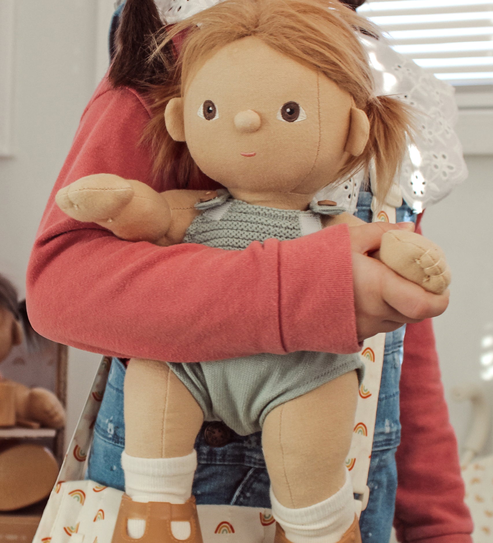 A close up of a child holding an Olli Ella Gigi Dinkum doll.