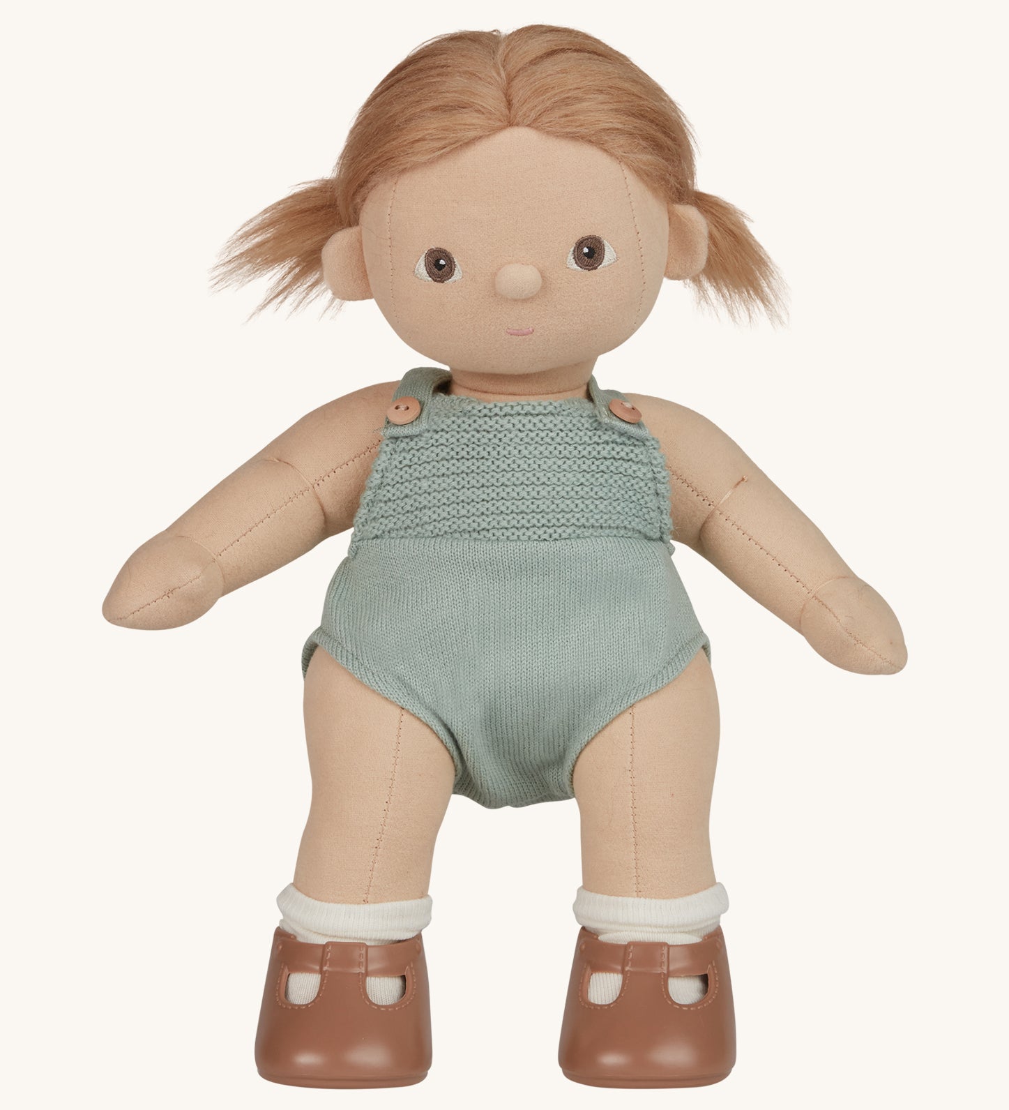 An Olli Ella Gigi Dinkum doll. The doll has blonde hair in pig tails and brown eyes. The doll is in a standing position and is wearing a mint green coloured knitted outfit and light brown coloured shoes. Shown on a plain background.  