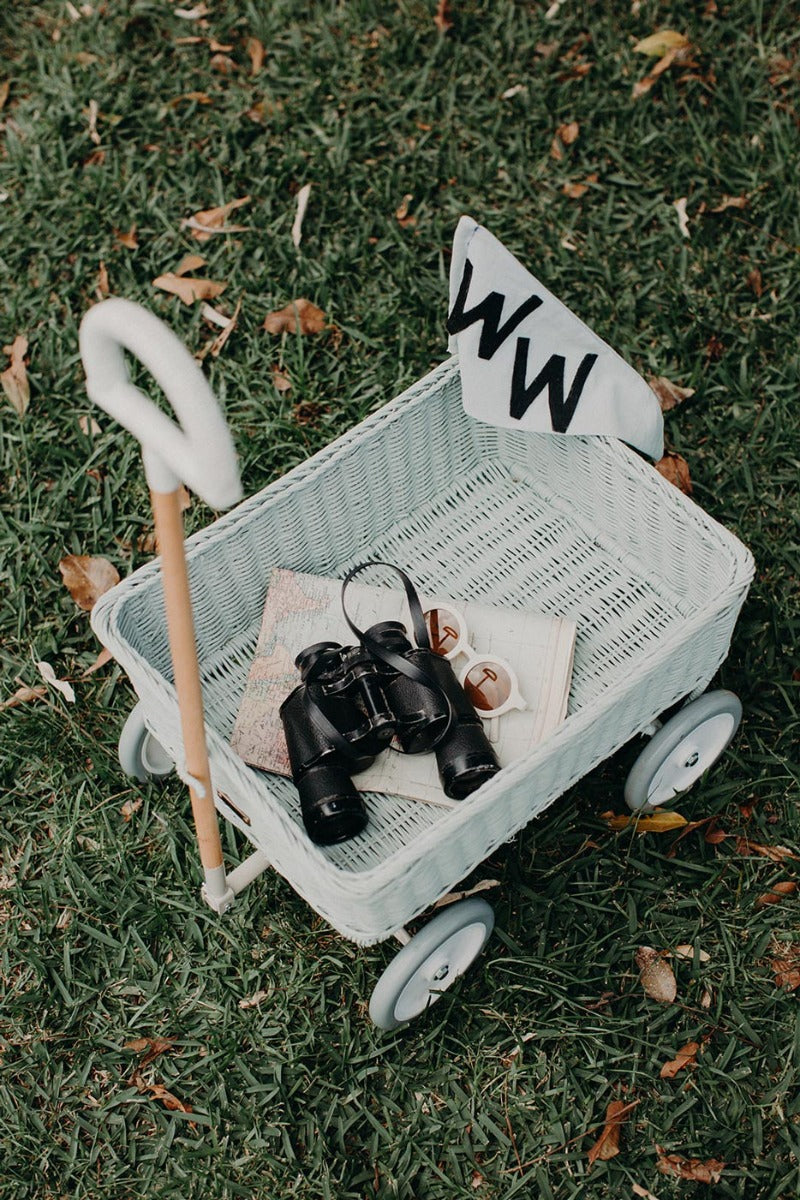 Black binoculars and a map inside the Olli Ella classic blue wonder wagon toy on some grass