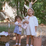 A child wearing the grey smoke coloured Olli Ella Fluffle Bunny Ear Headband, they are holding dozy dinkums.