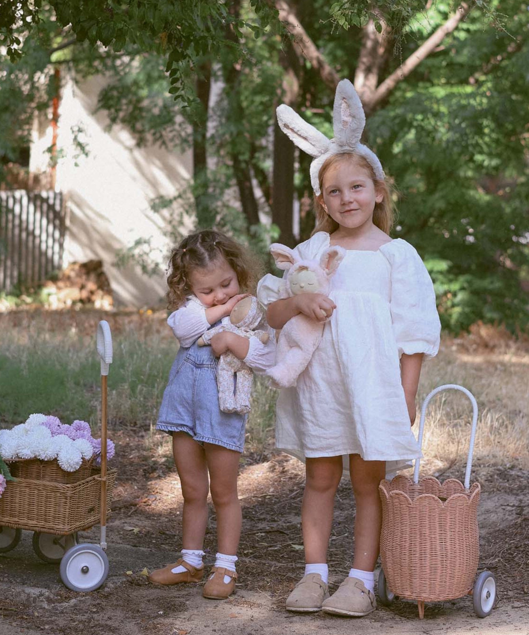 A child wearing the grey smoke coloured Olli Ella Fluffle Bunny Ear Headband, they are holding dozy dinkums.