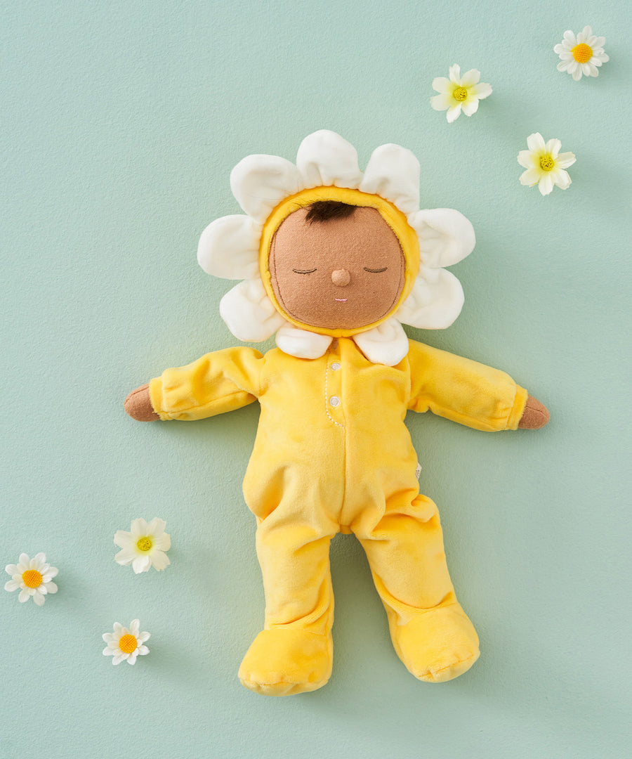 Olli Ella Buttercup Pip Dozy Dinkum Doll laying on a light green surface surrounded by white flower heads.