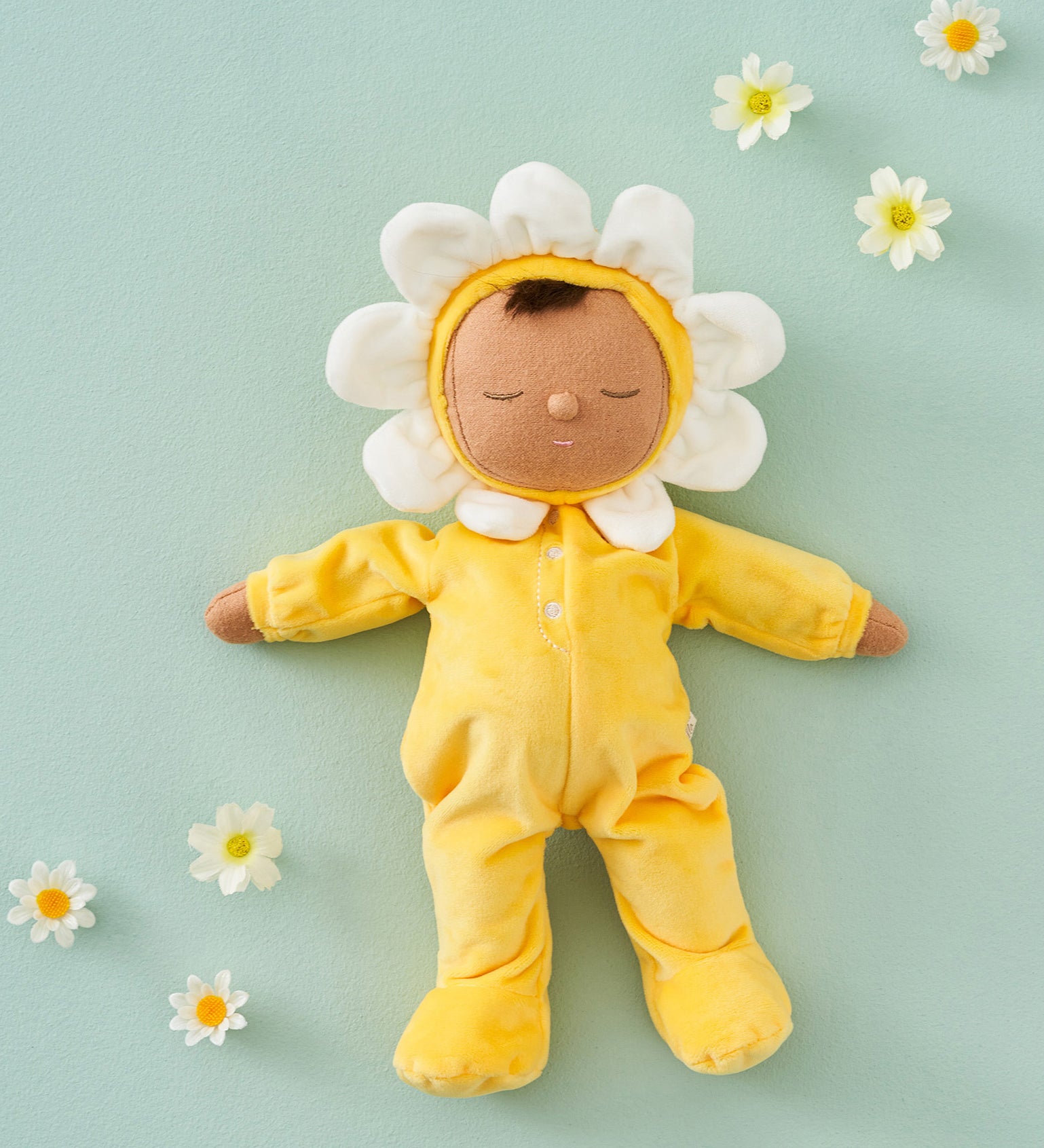 Olli Ella Buttercup Pip Dozy Dinkum Doll laying on a light green surface surrounded by white flower heads.