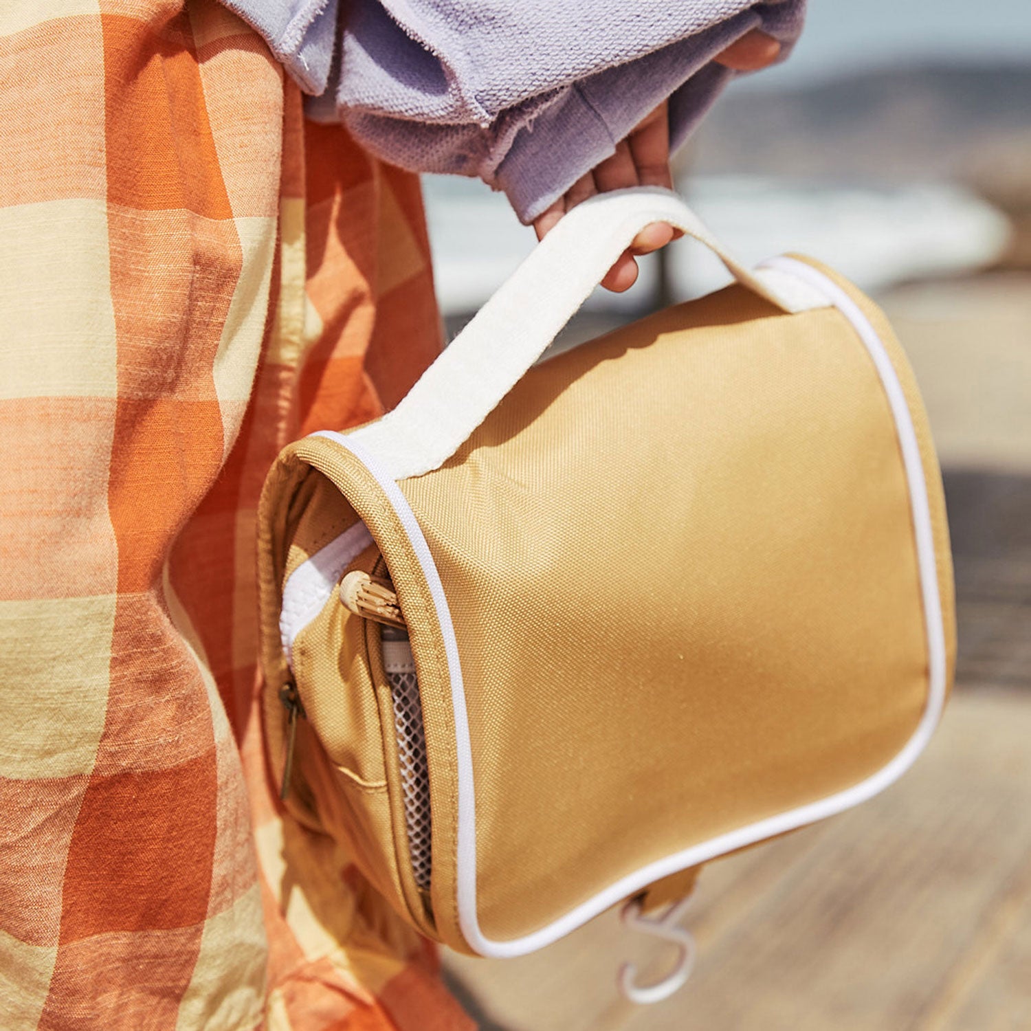 Close up of a child holing the Olli Ella Butterscotch See-Ya Wash Bag