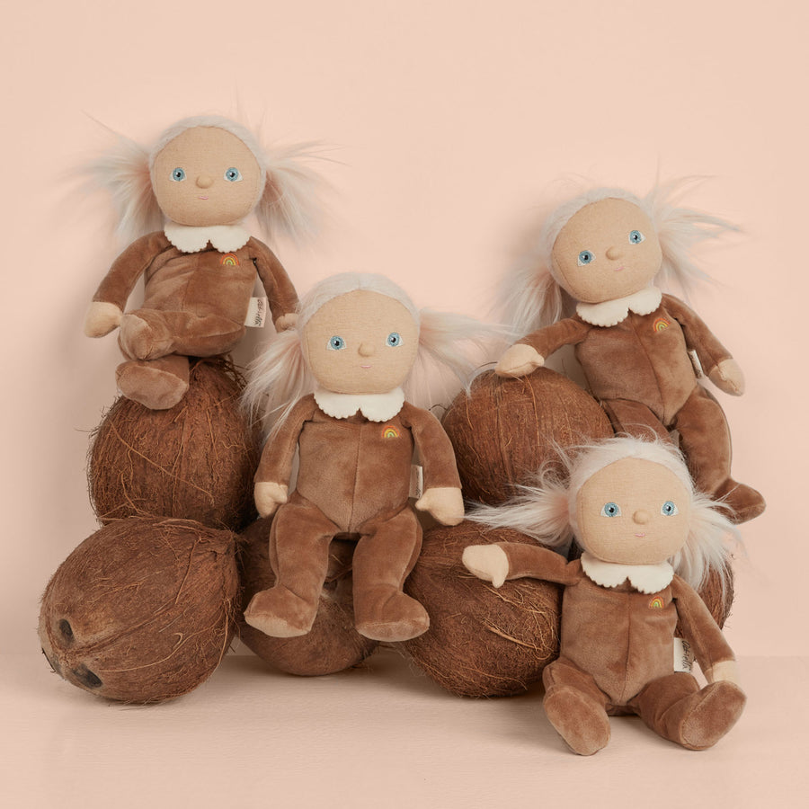 Group of Olli ella coco coconut dinky dolls sat on top of a pile of coconuts on a pink background