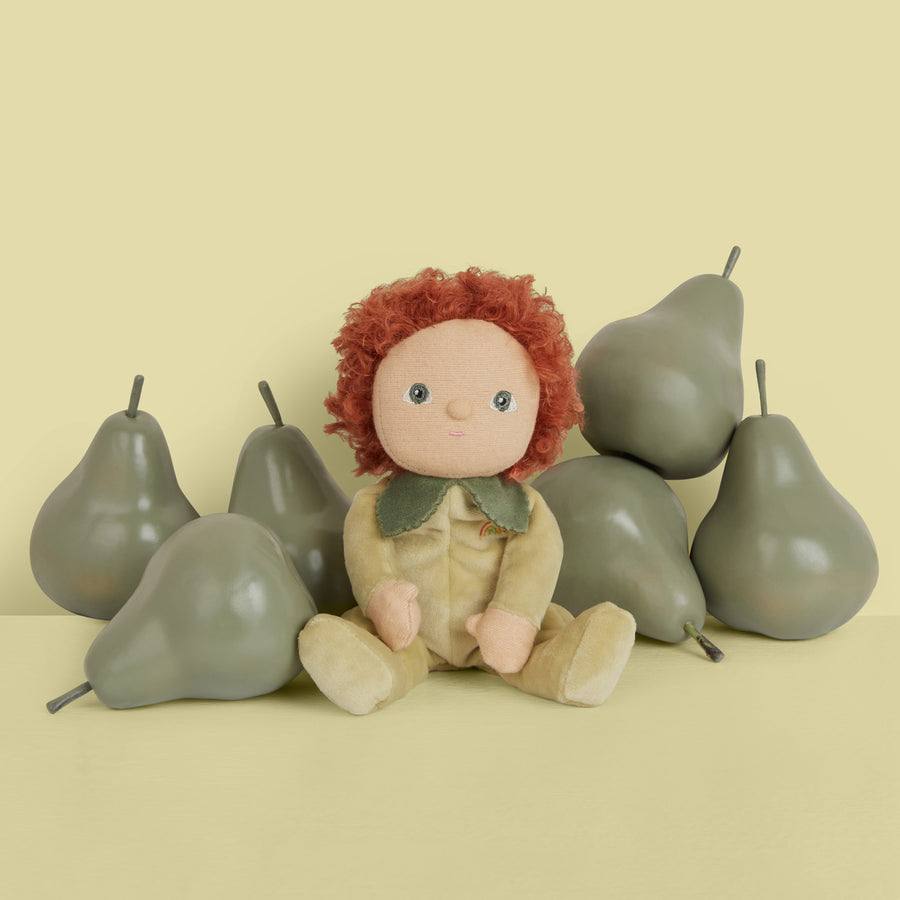 Olli Ella green dinky doll toy sat next to a pile of pears on a green background