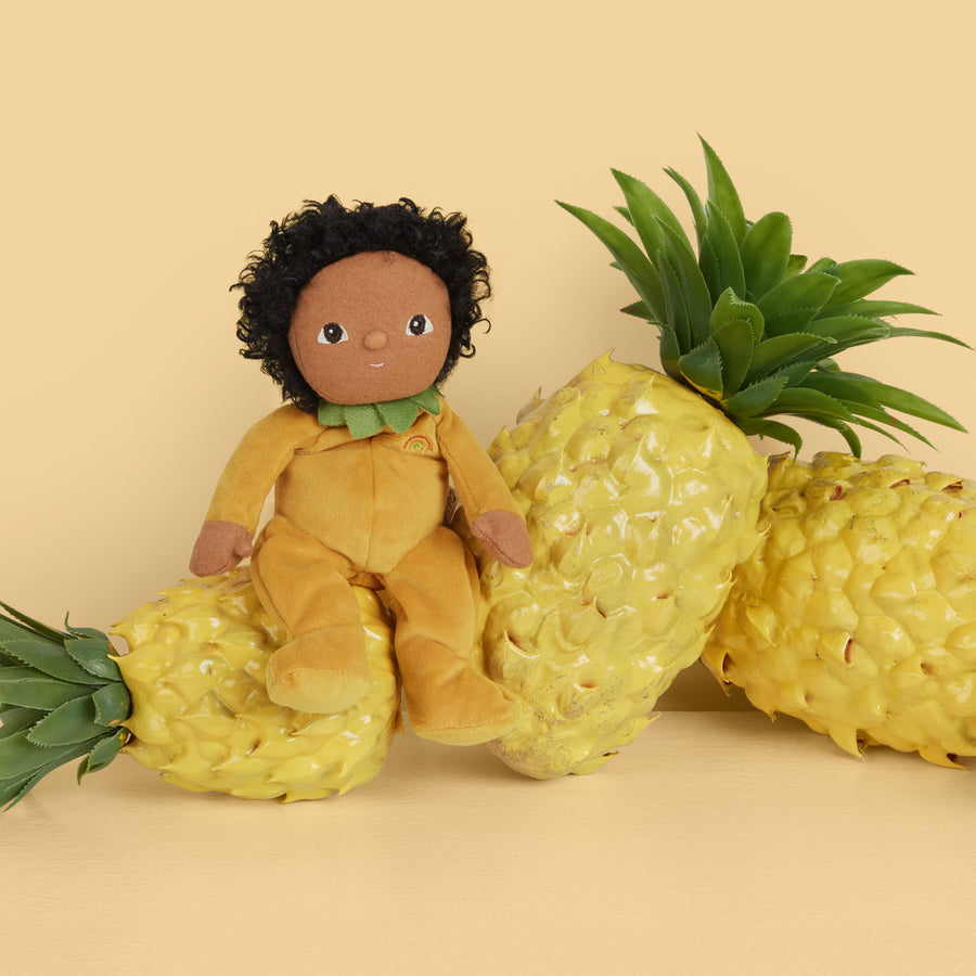 Yellow olli ella dinky dinkum doll sat on some pineapples on a yellow background