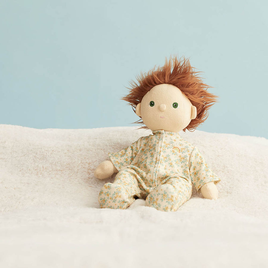 Olli Ella dinkum doll sat on a white blanket wearing the vintage blossom print doll pyjamas