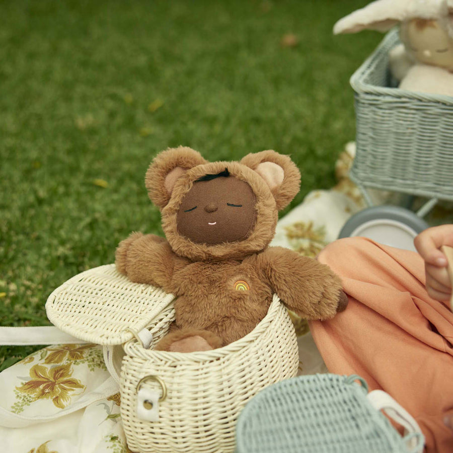 Close up of an Olli ella cozy dozy dinkum doll laying in the Olli ella childrens natural rattan chari bag