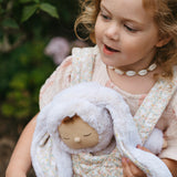 A close up of a child carrying the Olli Ella Bunny Lala Cozy Dinkum in a Olli Ella toy carrier. 