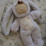 The Olli Ella Bunny Lala Cozy Dinkum soft toy laying on a floral patterned blanket. 