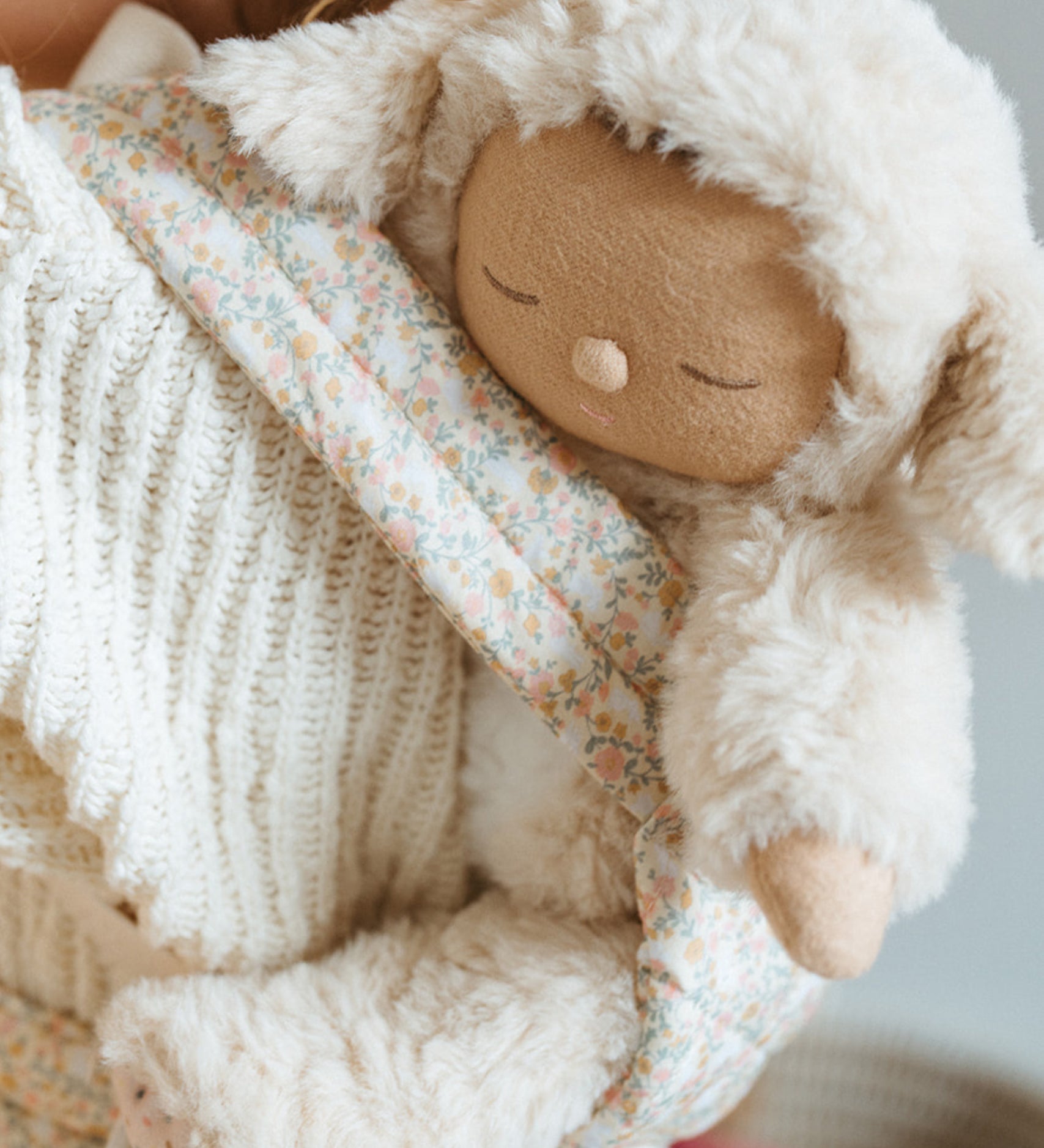 A close up of the Lamby Picket Olli Ella Cozy Dinkum Doll in a toy carrier. 