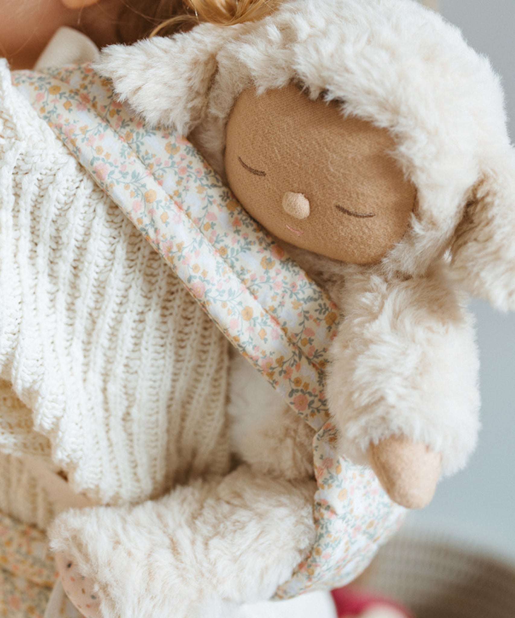 A close up of the Lamby Picket Olli Ella Cozy Dinkum Doll in a toy carrier. 