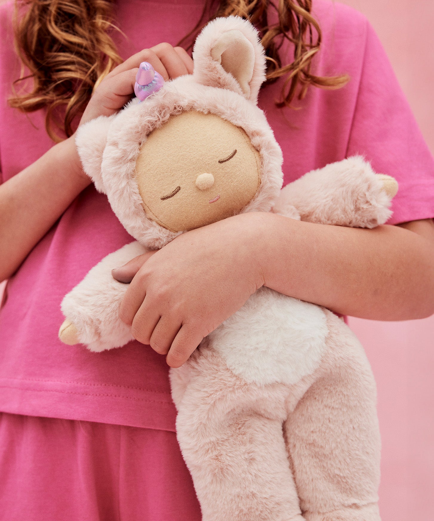 A child holding the pink fluffy Olli Ella dinkum doll 