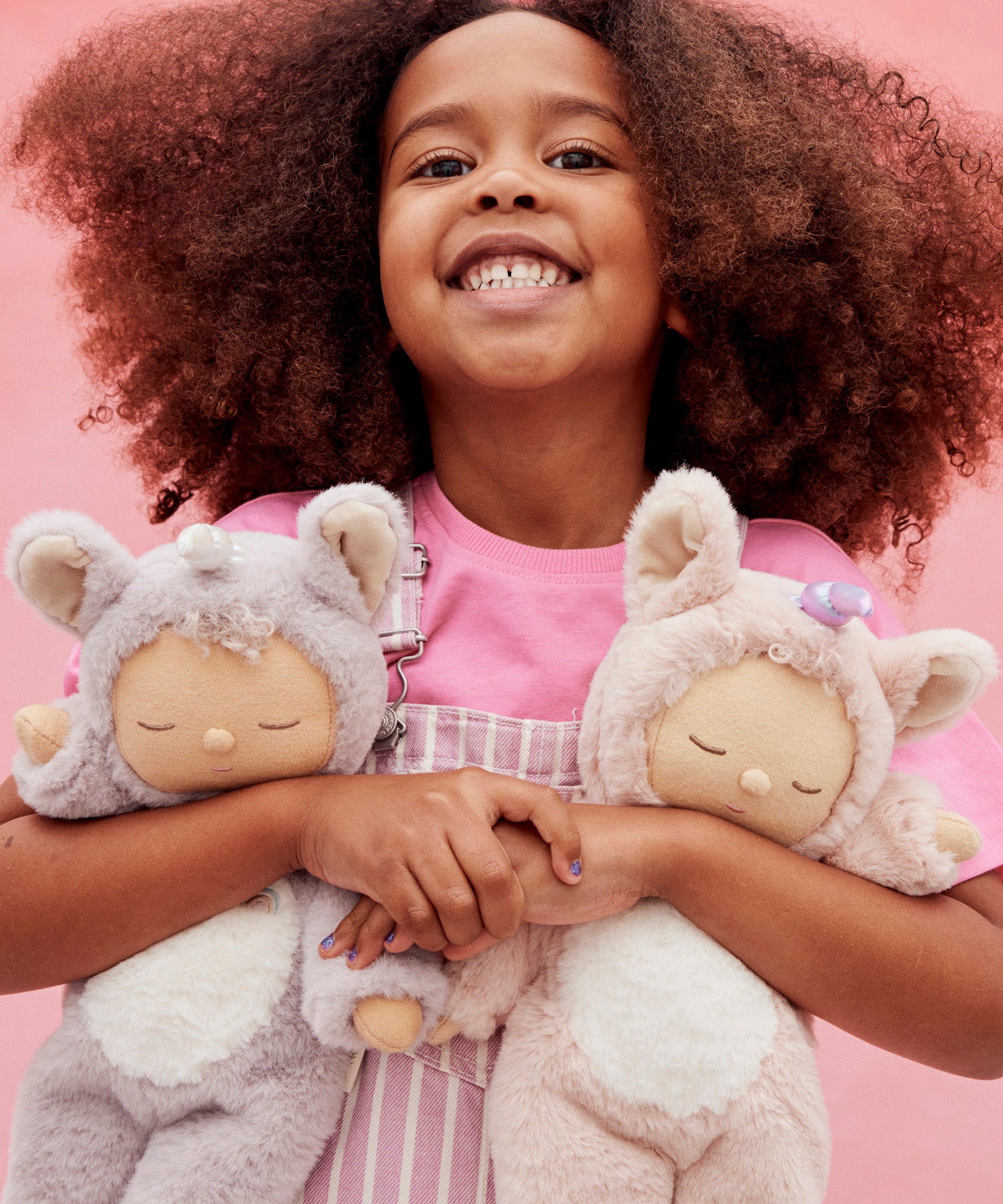 A child holding the lilac and pink fluffy Olli Ella dinkum dolls 