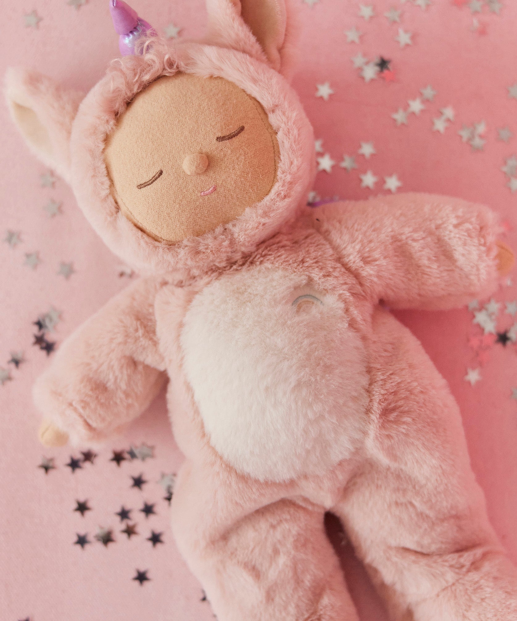 A lifestyle photo of the pink Olli Ella unicorn cosy dinkum doll.