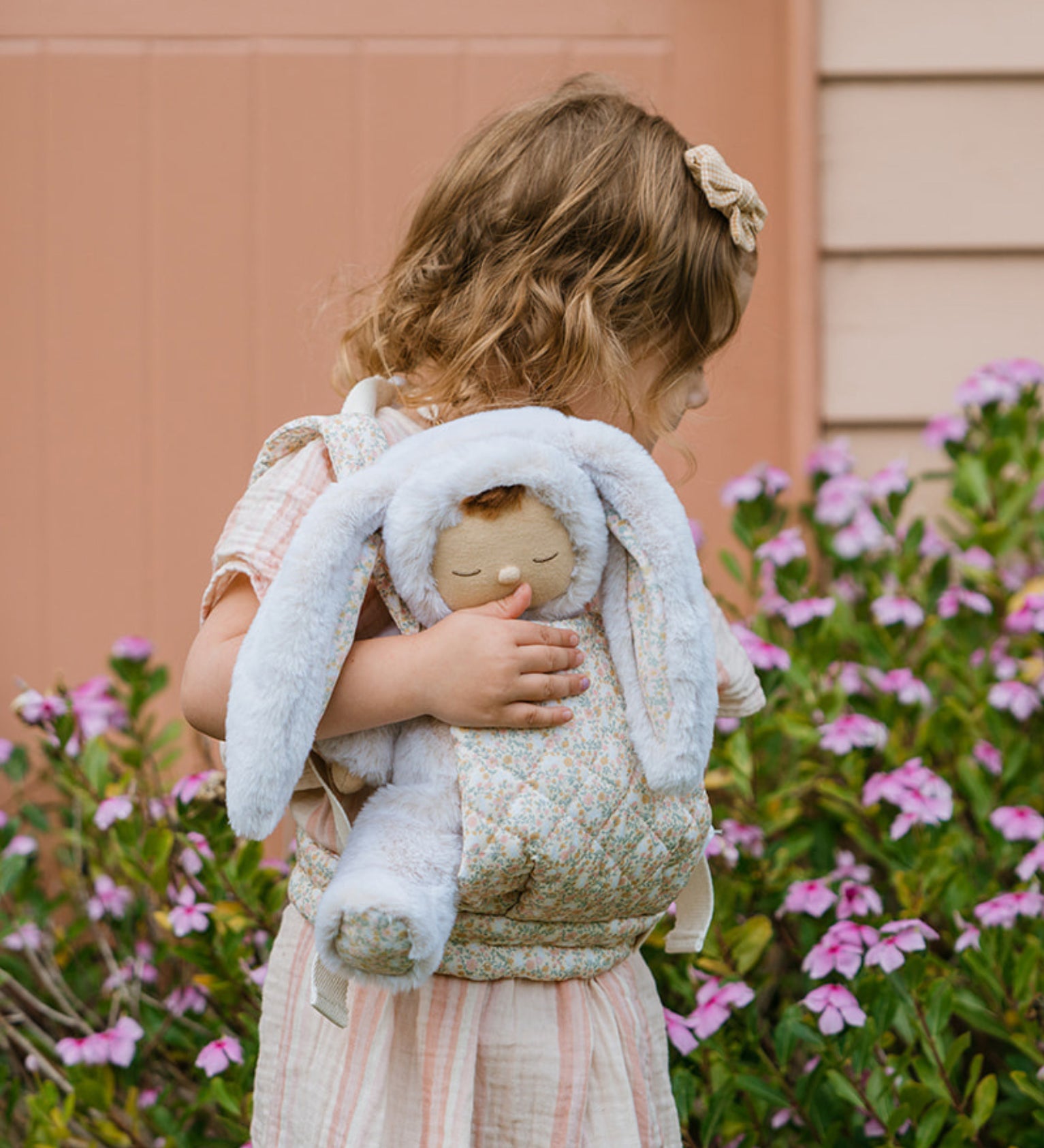 A child carrying the Olli Ella Bunny Lala Cozy Dinkum in a Olli Ella toy carrier. 