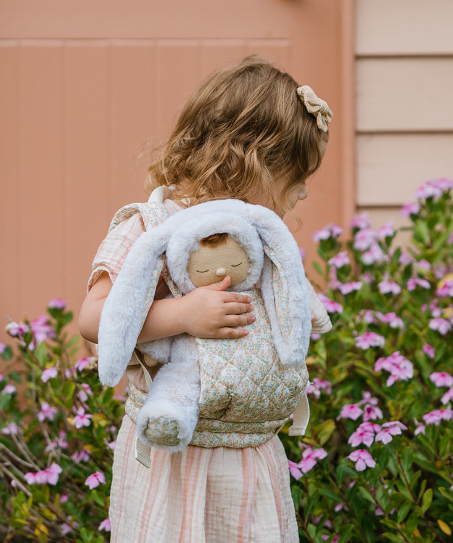 A child carrying the Olli Ella Bunny Lala Cozy Dinkum in a Olli Ella toy carrier. 