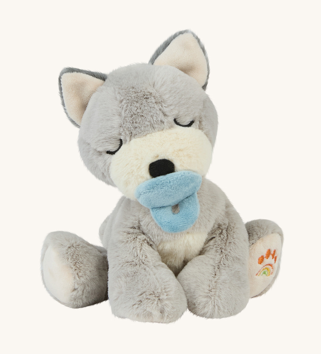 A soft grey sitting Olli Ella dinkum puppy with a magnetic dog toy on its mouth on a cream background.