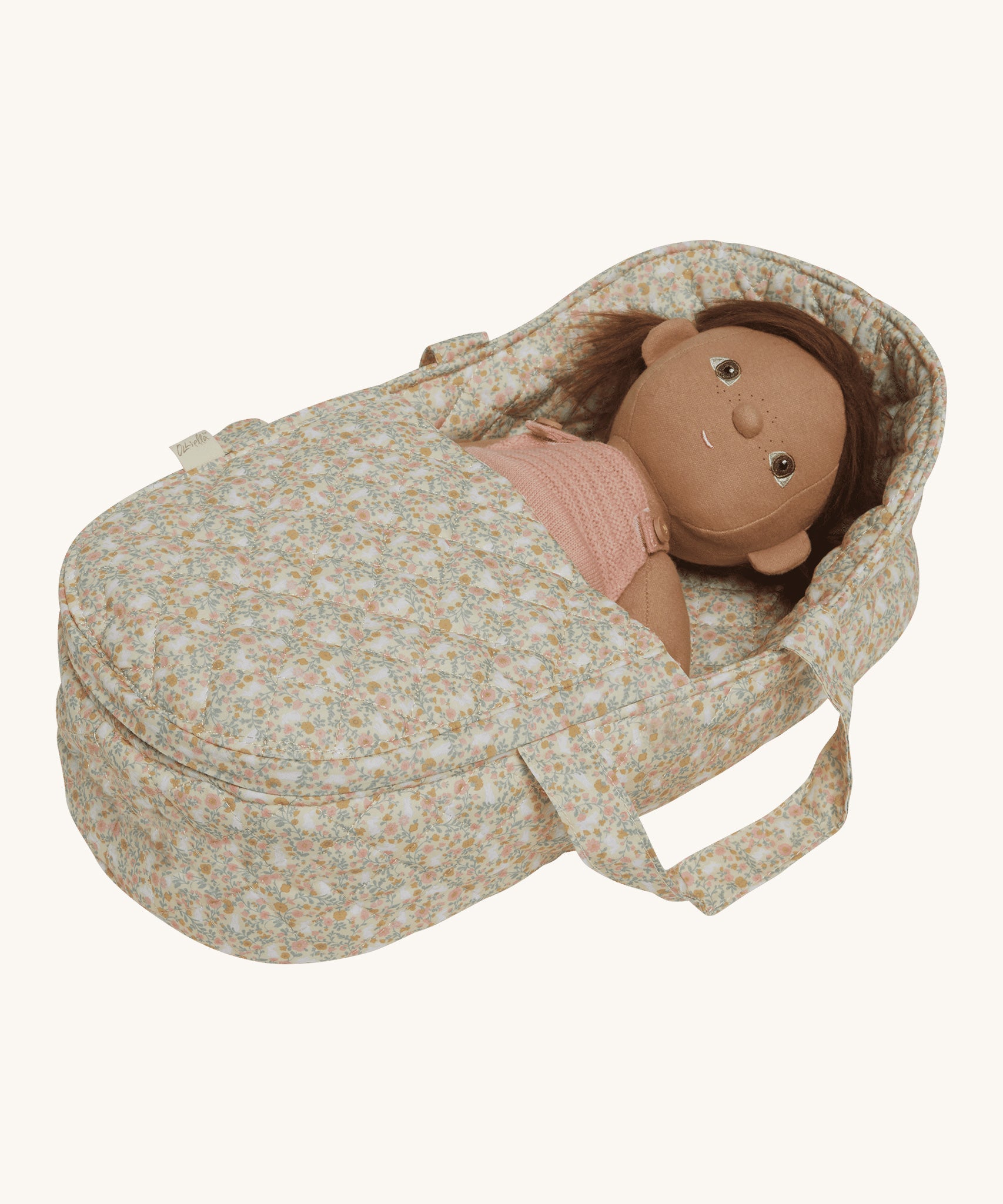 A dunkum Doll laying in the Olli Ella Garden Floral Gardenia print Dinkum Dolls Quilted Carry Cot 