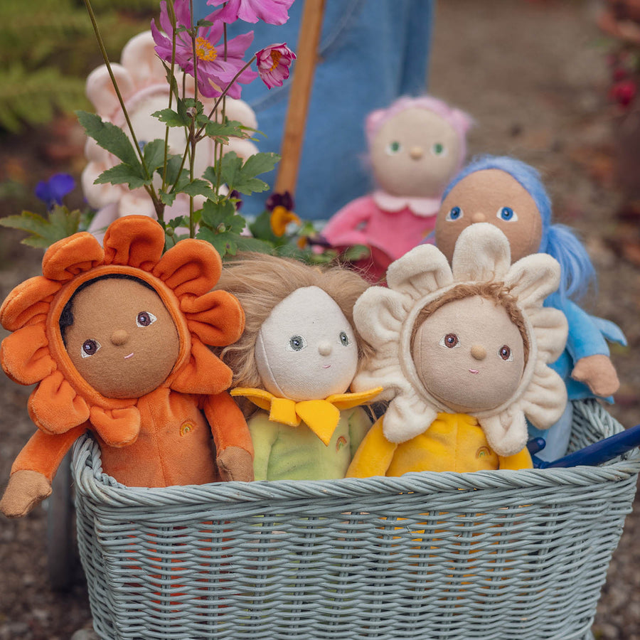 Olli Ella Dinky Dinkum Blossom Buds sat in an Ollie Ella wagon with a child holding two Rose and Lily dolls