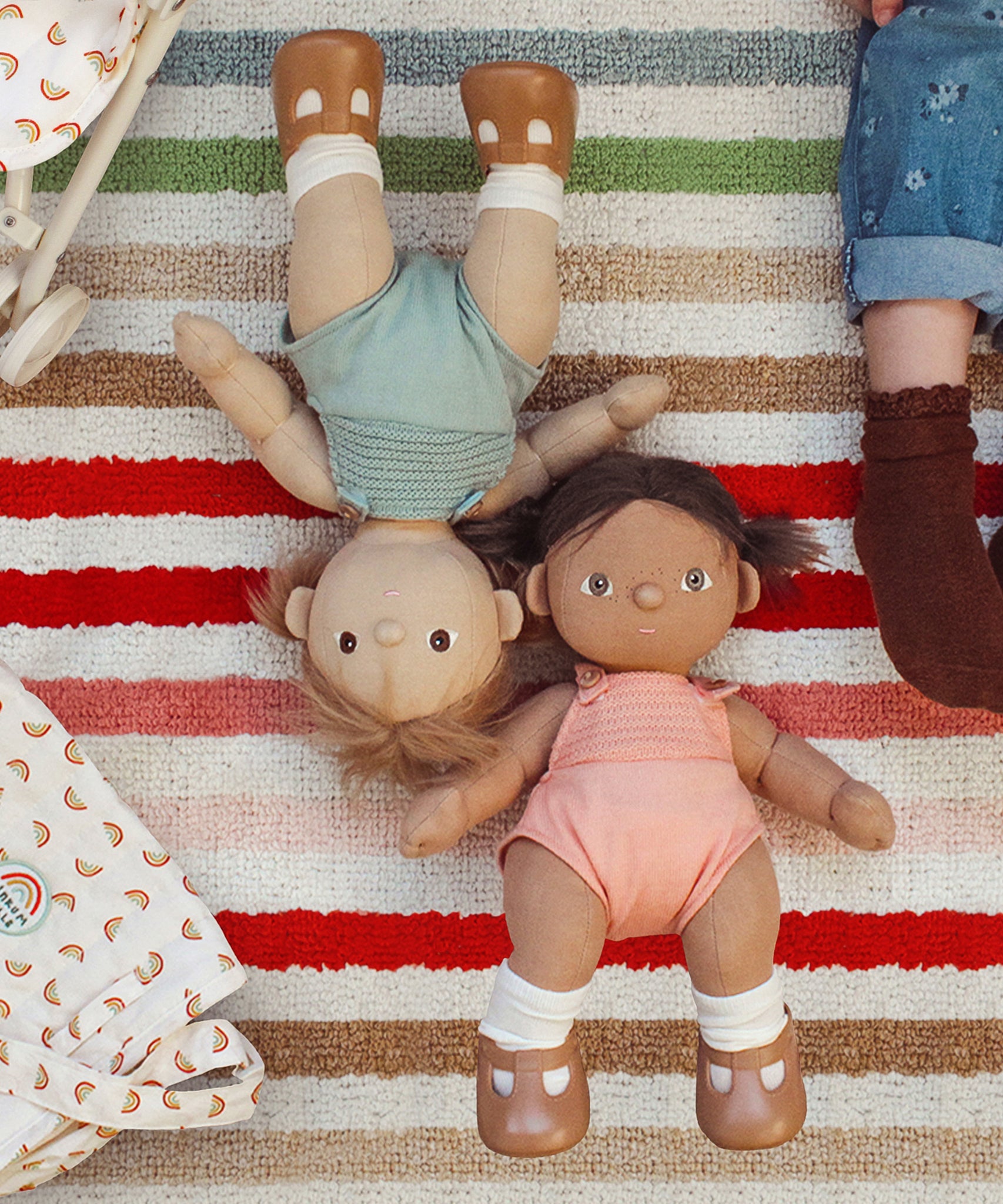 Olli Ella Gigi and Dottie Dinkum Dolls laying on a striped towel. 