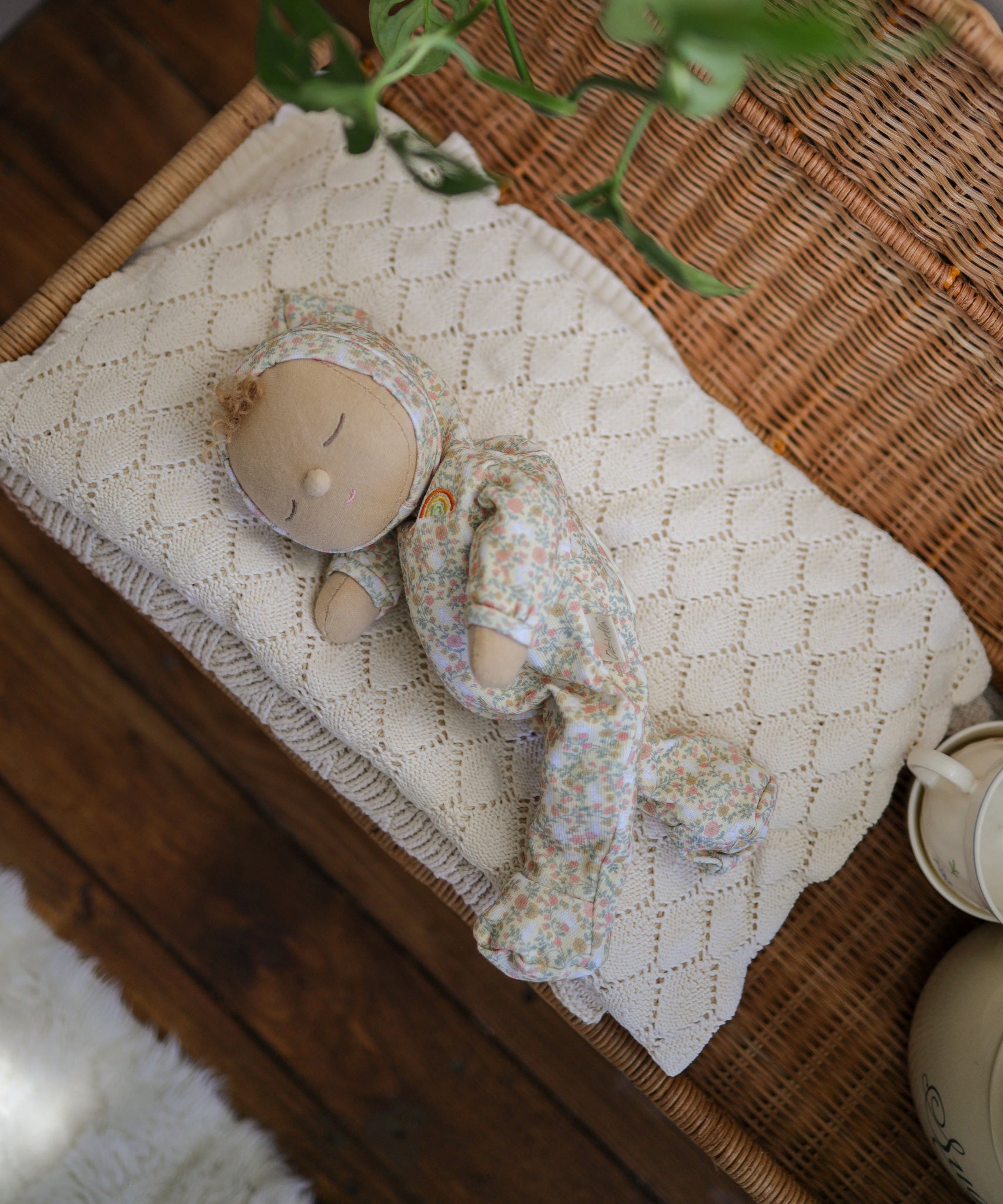 A Olli Ella Dozy Dinkum Doll Custard placed on a cream coloured blanket.