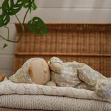 A side on view of an Olli Ella Dozy Dinkum Doll Custard laying on a pile of blankets.