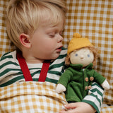 Toddler asleep next to Charlie Chestnut a Dress Me Dinky Doll by Olli Ella, with yellow gingham bedding.