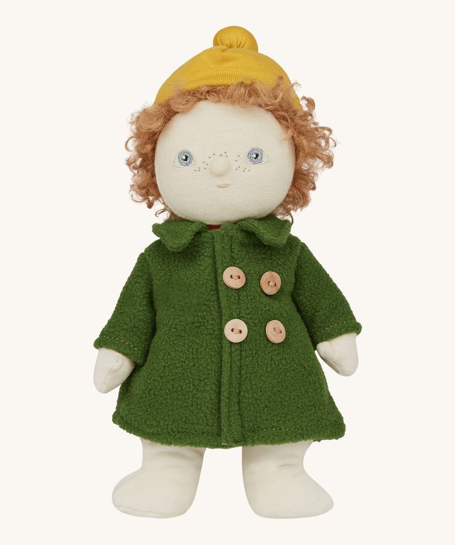 Charlie Chestnut is a Dress Me Dinky Doll by Olli Ella, complete with a removable cosy green fleece trench coat, yellow bobble beanie hat . Sat down, cream background.