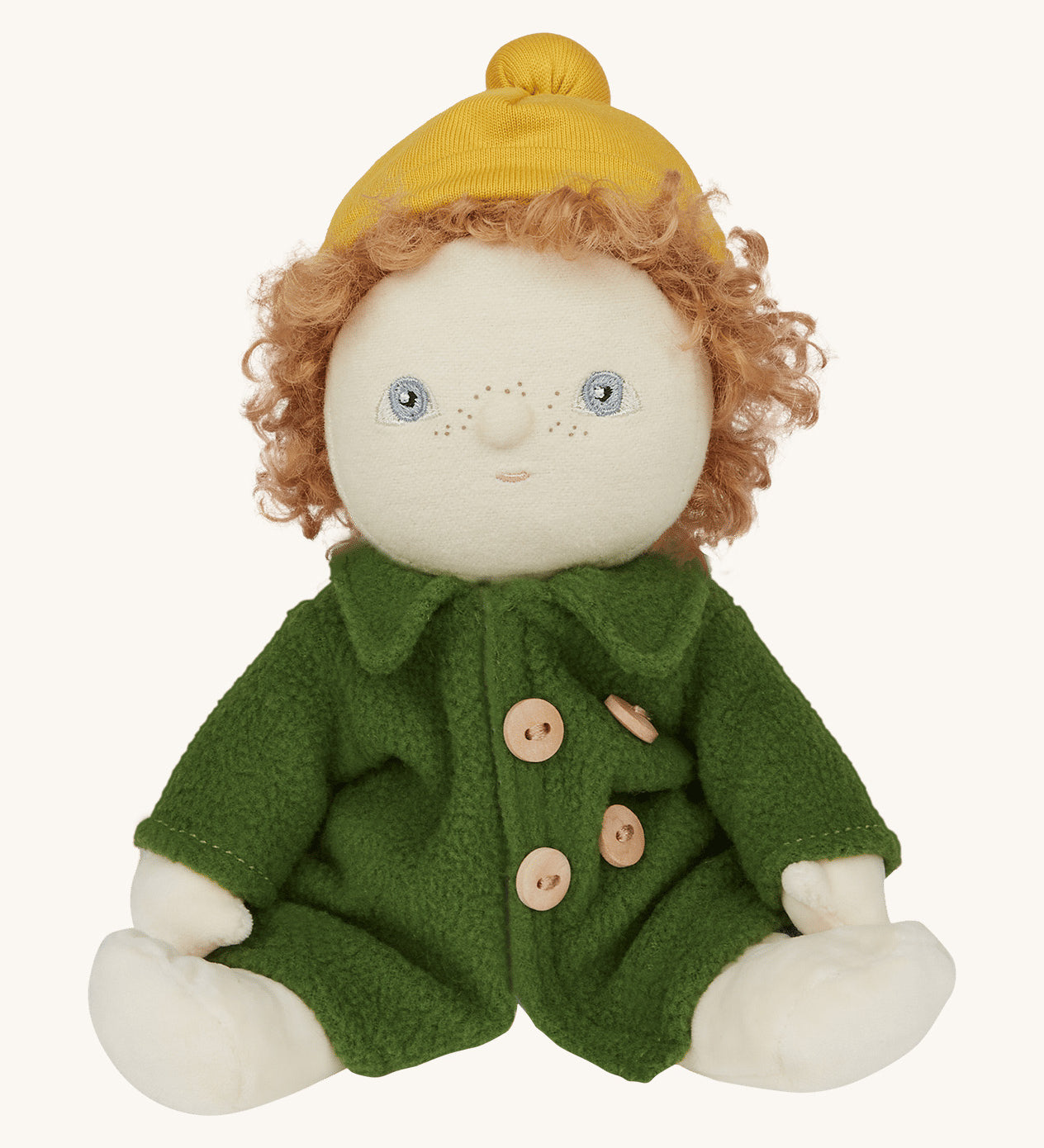 Charlie Chestnut is a Dress Me Dinky Doll by Olli Ella, complete with a removable cosy green fleece trench coat, yellow bobble beanie hat . Sat down, cream background.