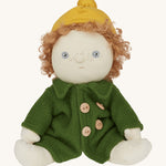 Charlie Chestnut is a Dress Me Dinky Doll by Olli Ella, complete with a removable cosy green fleece trench coat, yellow bobble beanie hat . Sat down, cream background.