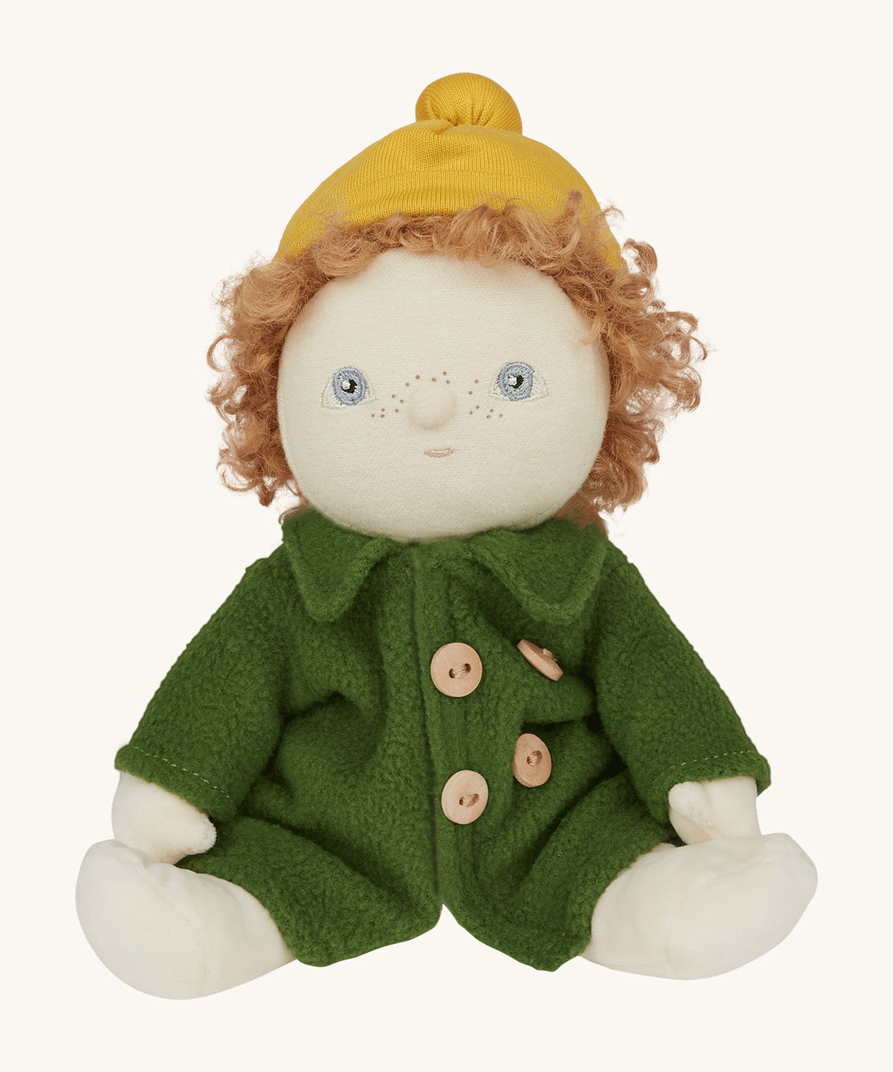 Charlie Chestnut is a Dress Me Dinky Doll by Olli Ella, complete with a removable cosy green fleece trench coat, yellow bobble beanie hat . Sat down, cream background.