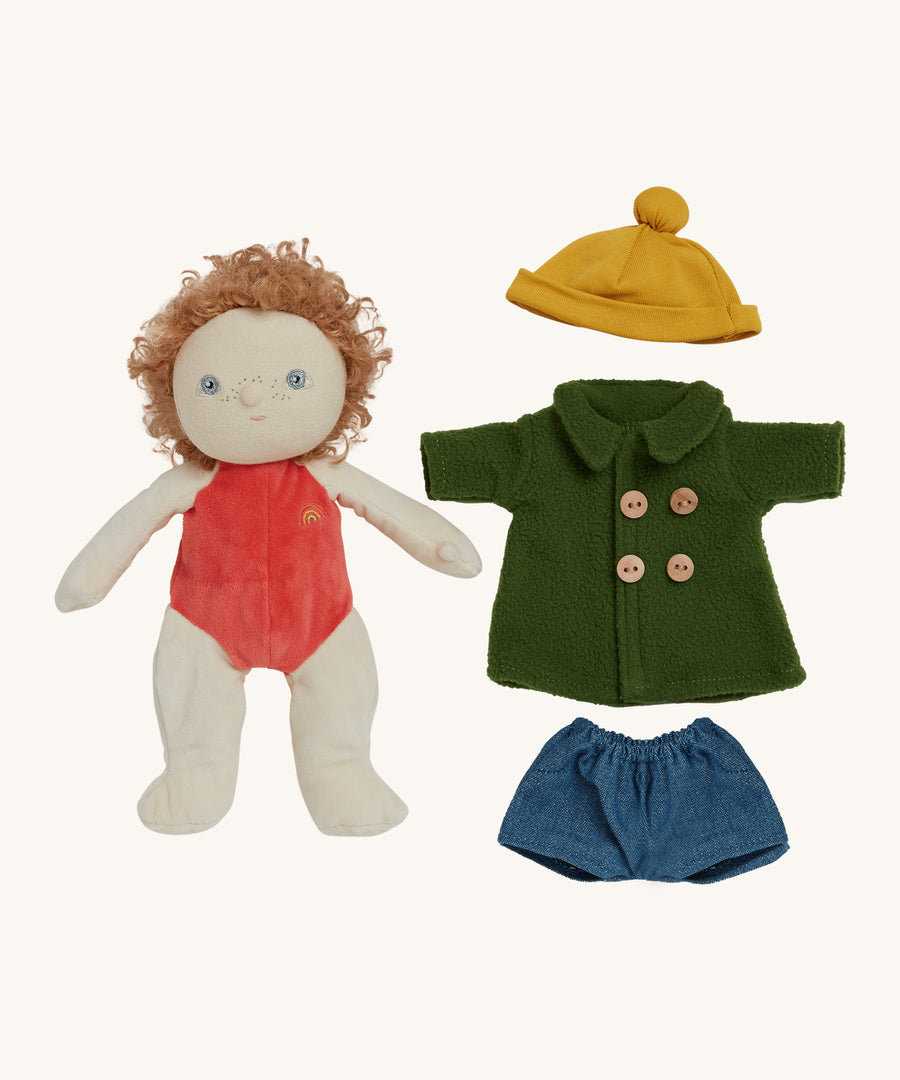 Charlie Chestnut Dress Me Dinky Doll by Olli Ella, without clothes. The green fleece trench coat, yellow bobble beanie hat and denim shorts next to him. Cream background. 