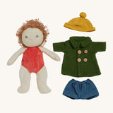 Charlie Chestnut Dress Me Dinky Doll by Olli Ella, without clothes. The green fleece trench coat, yellow bobble beanie hat and denim shorts next to him. Cream background. 