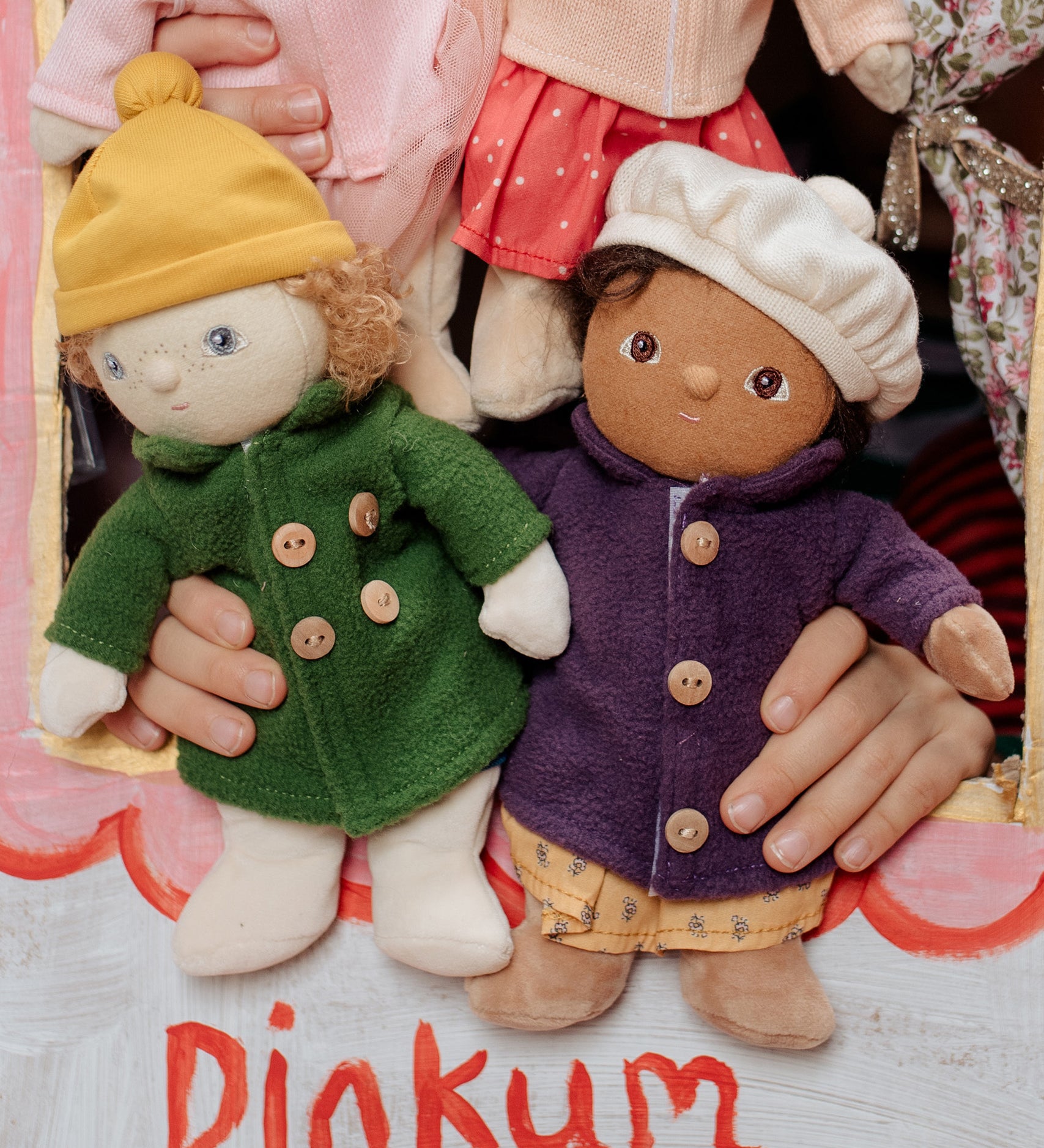 Two Dress Me Dinky dolls in a puppet show being held by a child. 