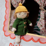 Charlie Chestnut is a Dress Me Dinky Doll by Olli Ella, complete with a removable cosy green fleece trench coat, yellow bobble beanie hat . At a child's puppet theatre.