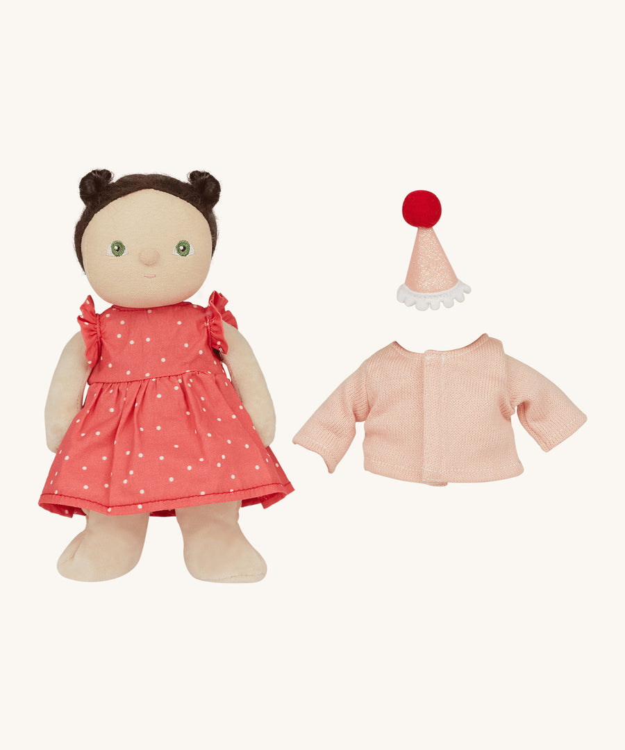 Olli Ella Dress Me Dinky - Sophie Sundae, a doll with brown hair and green eyes wearing a pink polka dot dress, her light pink cardigan and a pink party hat is next to her. Cream background.