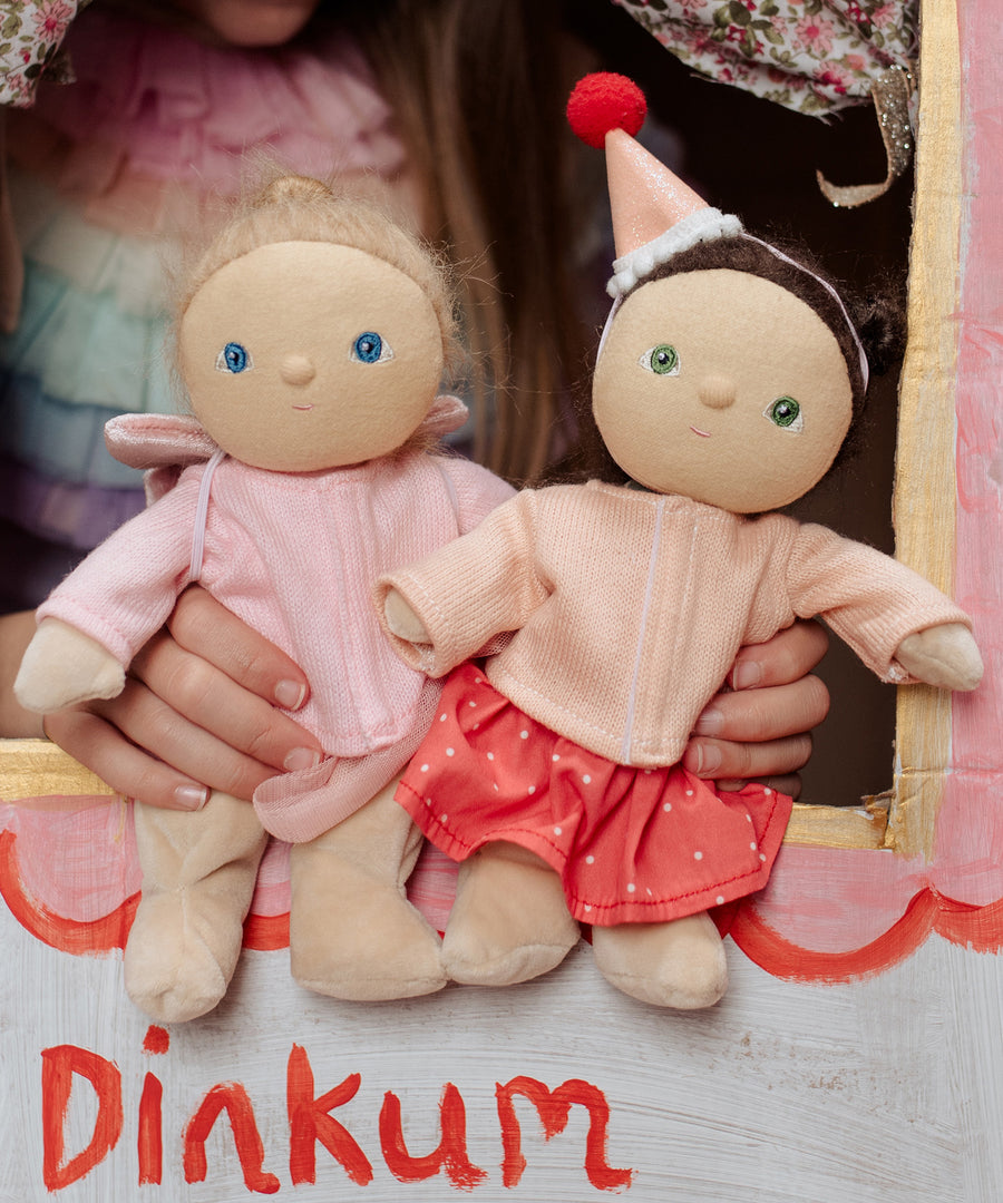 Two Dress Me Dinky dolls in a puppet show being held by a child. 