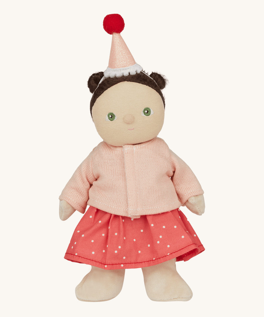 Olli Ella Dress Me Dinky - Sophie Sundae, a doll with brown hair and green eyes wearing a pink polka dot dress, light pink cardigan and a pink party hat. Cream background.