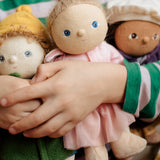 Three Dress Me Dinky dolls being held by a child in a green and white stripe top. 